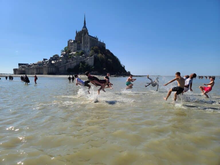 Élèves du Lycée Professionnel Rural Saint-Joseph de Châteaubriant se baignant et sautant dans l'eau lors d'une journée d'intégration, face au Mont-Saint-Michel.